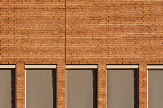Minimalist view of a brick facade with symmetrical windows casting shadows.