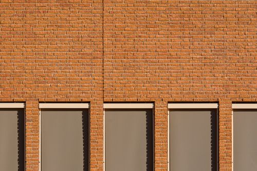 Free Minimalist view of a brick facade with symmetrical windows casting shadows. Stock Photo