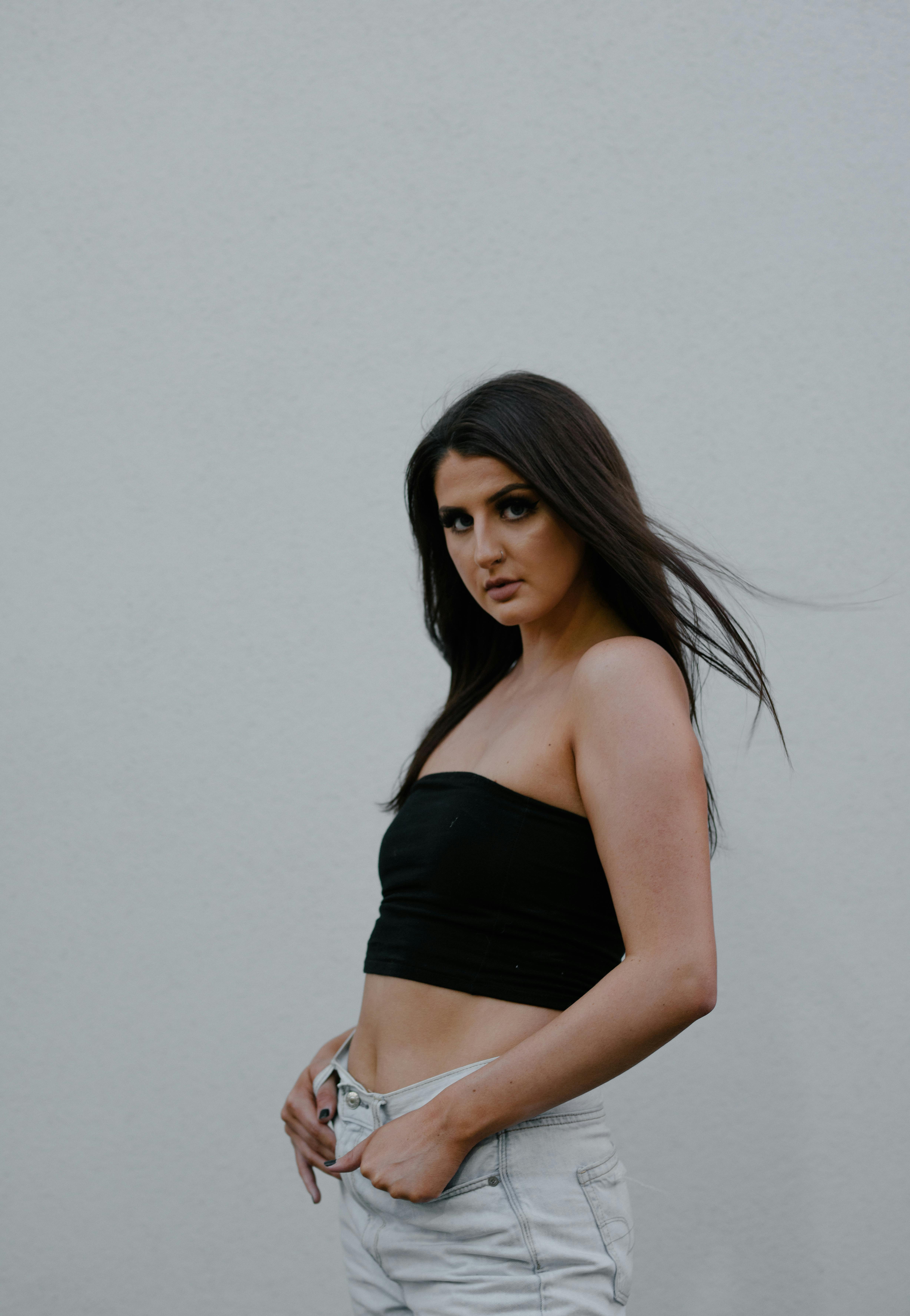 时装模特身着黑色露脐上衣，在白色背景下优雅展现现代风格
