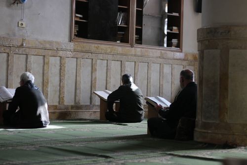 Free Three men reading Quran and praying inside a mosque in Idlib, Syria. Stock Photo