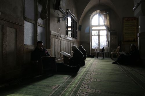 Free Peaceful scene of men reading and praying inside a historic mosque in Idlib, Syria. Stock Photo
