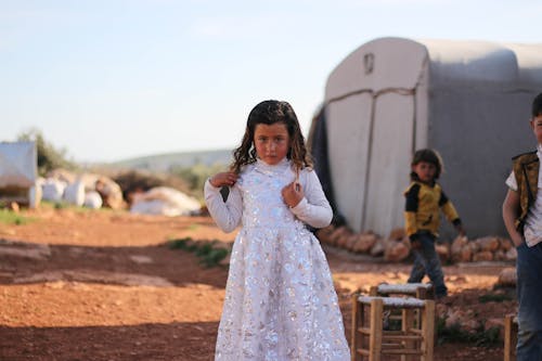 Free A Little Girl in a White Dress Standing Outside  Stock Photo