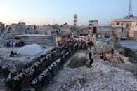 Large group dining in war-torn Idlib, Syria. Community gathered for a shared meal in outdoor urban rubble.