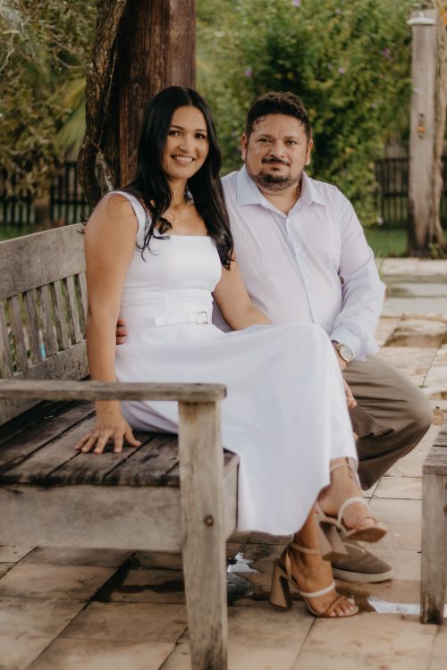 Free A well-dressed couple sitting happily on a wooden bench outdoors during summer. Stock Photo