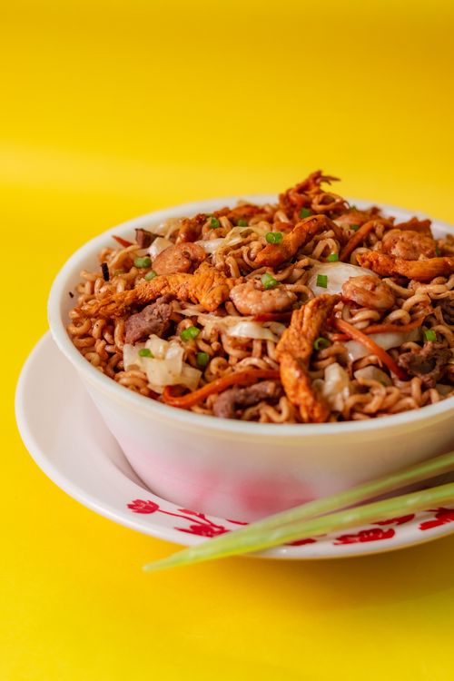 Free Appetizing chicken noodles in a colorful bowl on a yellow background, perfect for food blogs. Stock Photo