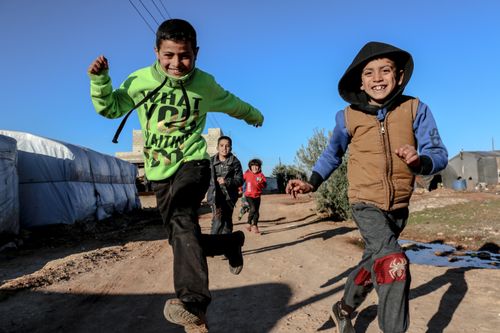 Free Children enjoying a sunny day at a camp in Idlib, Syria, expressing happiness and friendship. Stock Photo