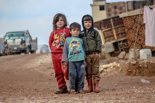 Free Three young children standing in a refugee camp in Idlib, Syria. Captured outdoors. Stock Photo