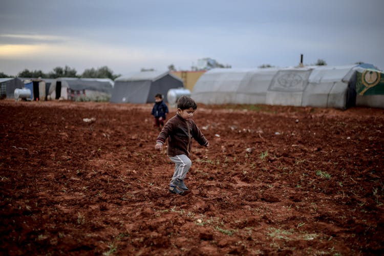 Little Children Running In The Mud At A Refugee Campsite 