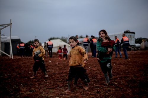 Free Children navigating a muddy field in Idlib, Syria, showing resilience amidst adversity. Stock Photo