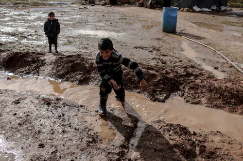 Free Boys enjoying playtime in a muddy field in Idlib, Syria after the rain. Stock Photo