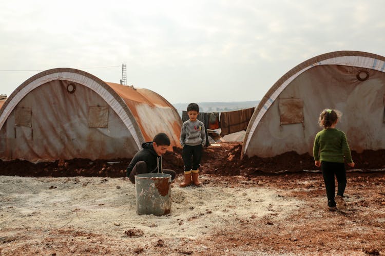 Children Playing In The Mud At A Refugee Campsite 