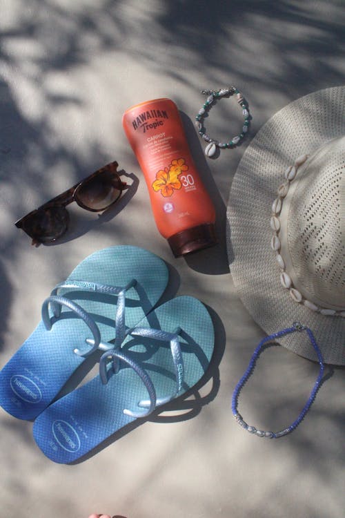 Free Shoes, Hat, Sunglasses and a Bottle of Sunscreen Lying in Sunlight  Stock Photo