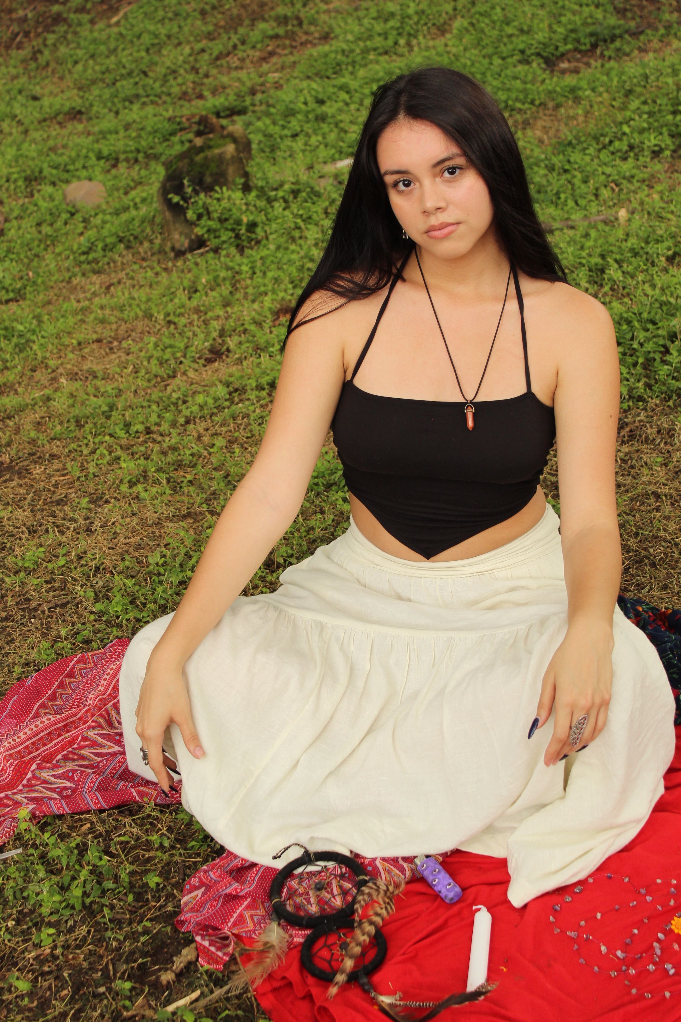 Free A woman in a black top and skirt sitting on the grass Stock Photo