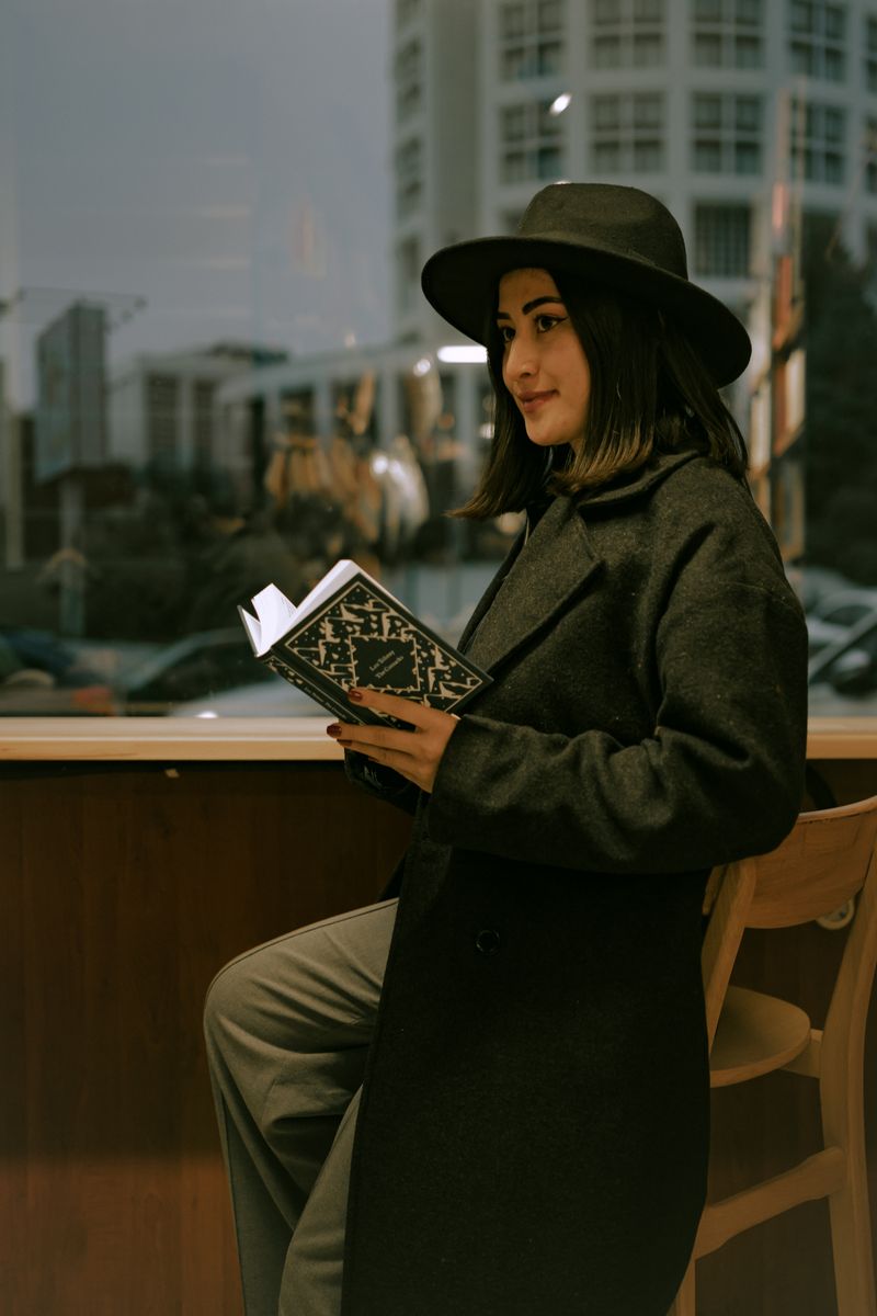 Woman in a black hat and wool coat reading in a library