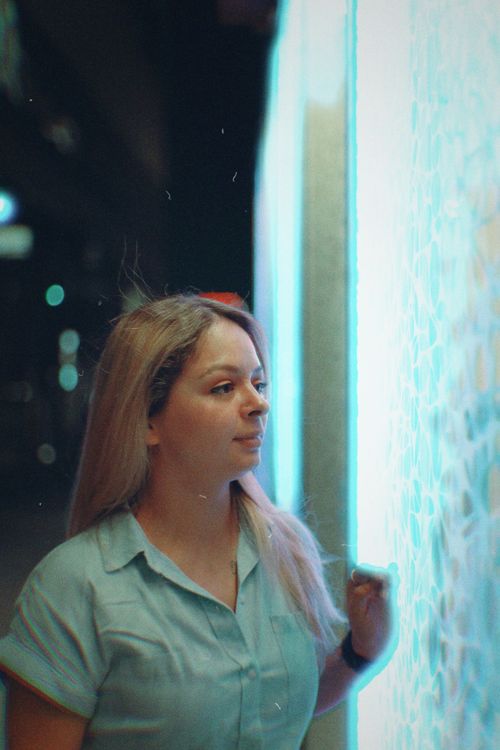 Free A young woman with blonde hair gazes at a glowing screen at night. Stock Photo