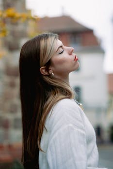 Portrait of a stylish woman standing in Berlin with eyes closed, embodying elegance and fashion.