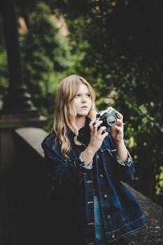 一名年轻女子在绿树成荫的户外拿着相机