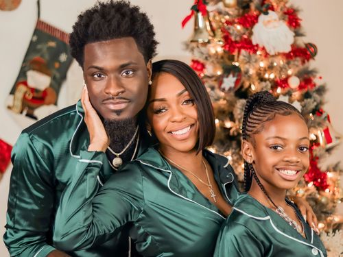 Free A joyful family in green pajamas celebrates Christmas by the festive tree. Stock Photo