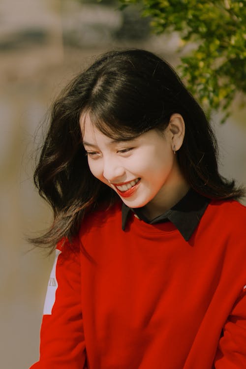 Smiling Young Model in a Red Sweatshirt With a Protruding Collar of a Black Blouse