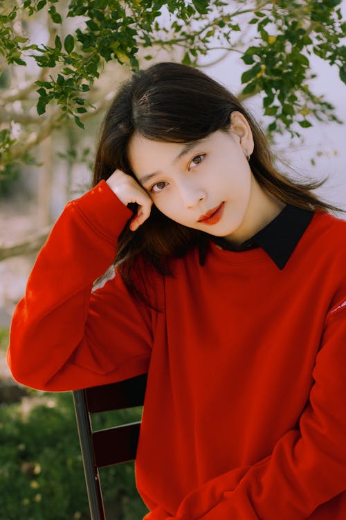 Model in Red Sweatshirt Sitting with Head Resting on Her Hand