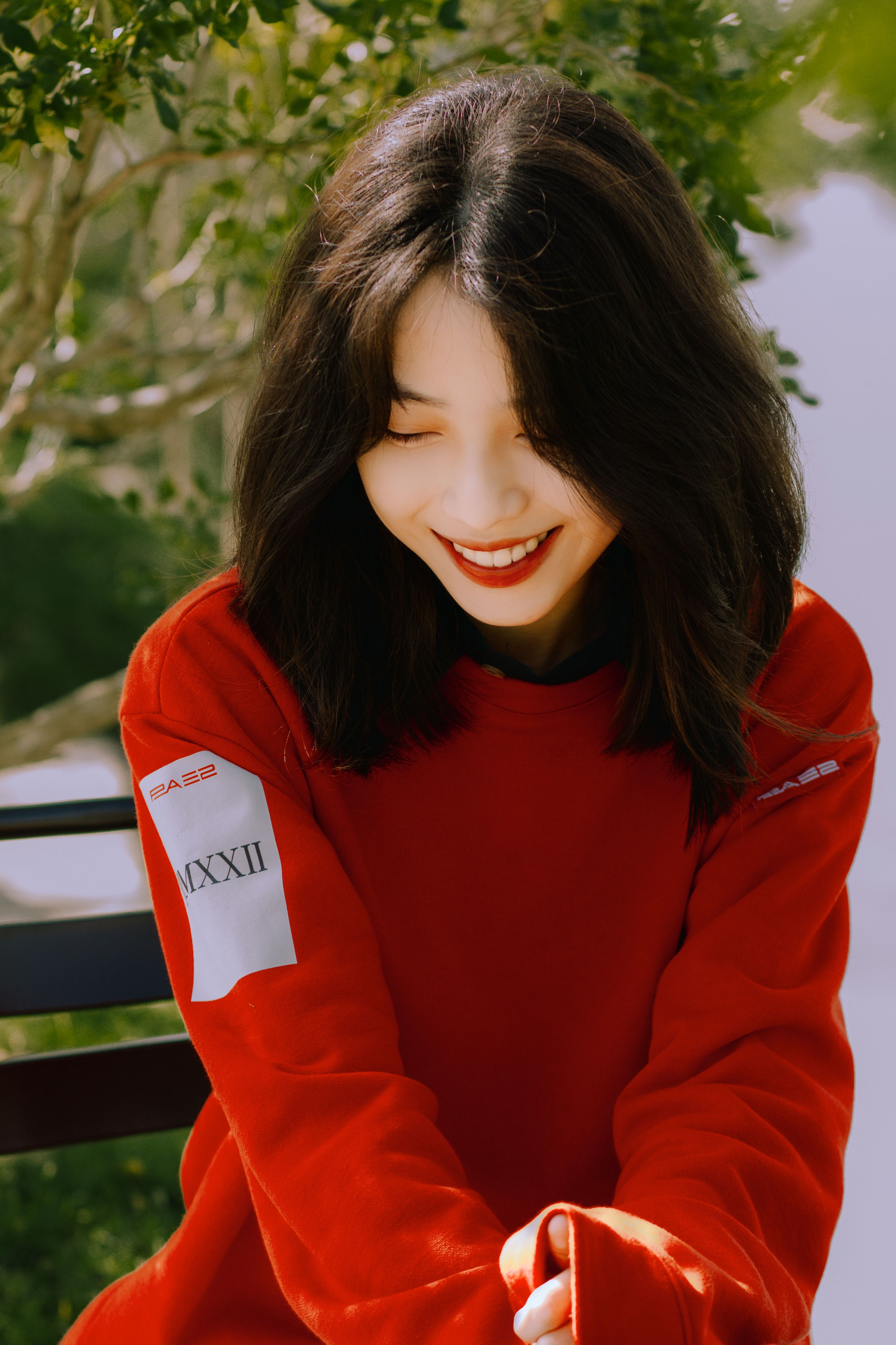 Beautiful portrait of an Asian woman in red clothes smiling outdoors.