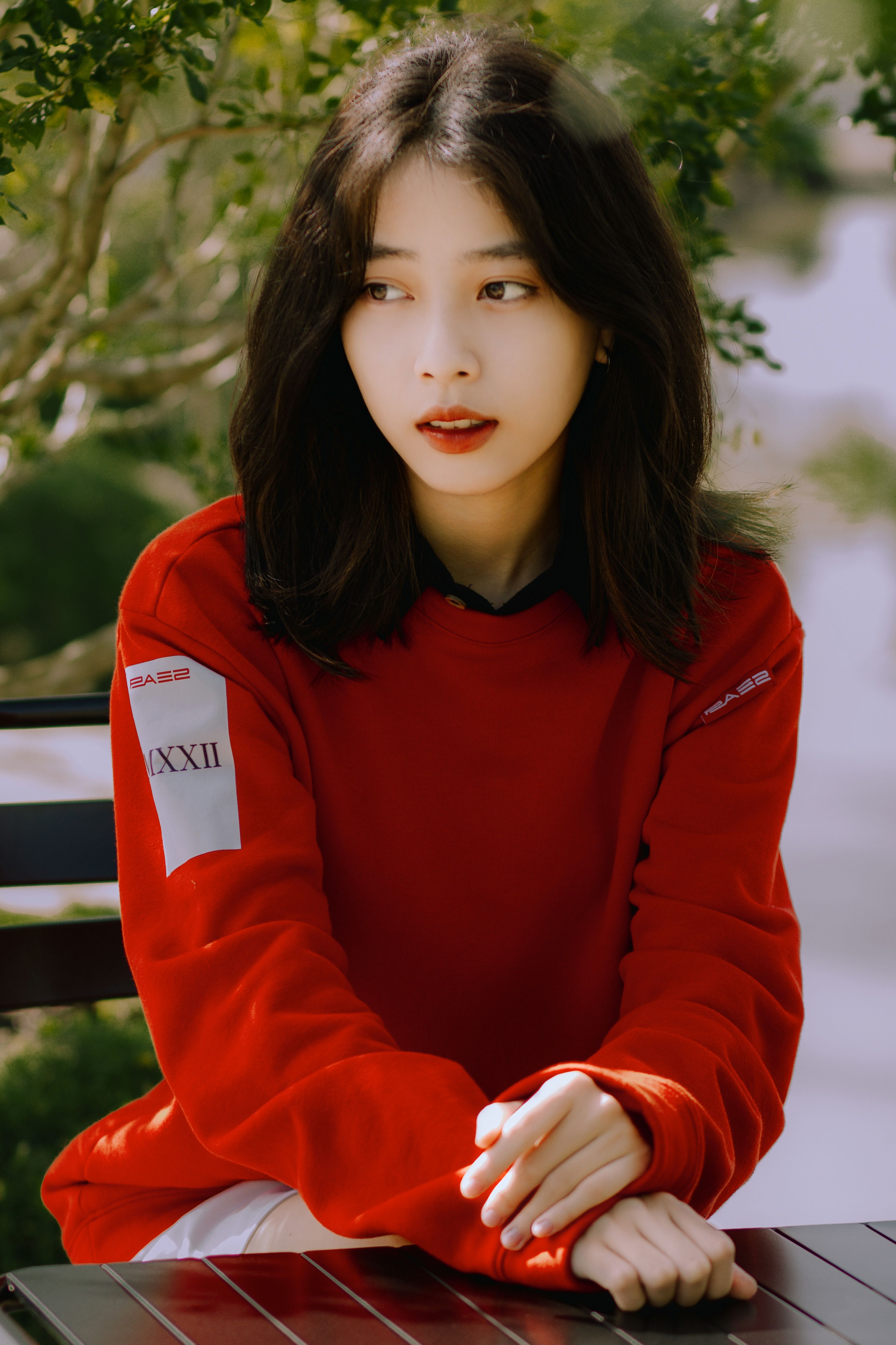 Portrait of an Asian woman in red attire sitting outdoors. Fashion and style captured beautifully.