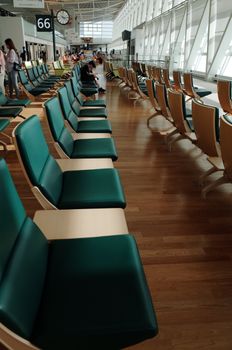 Spacious airport waiting area with green cushioned chairs and natural lighting at Hokkaido's New Chitose Airport.