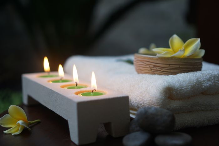 Lit spa candles with white flowers creating a calm relaxation setting
