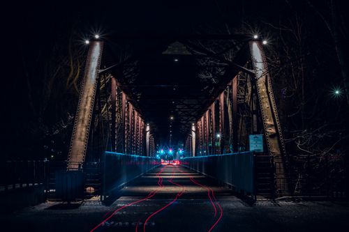 Free Long exposure night shot capturing light streaks over an illuminated urban bridge. Stock Photo