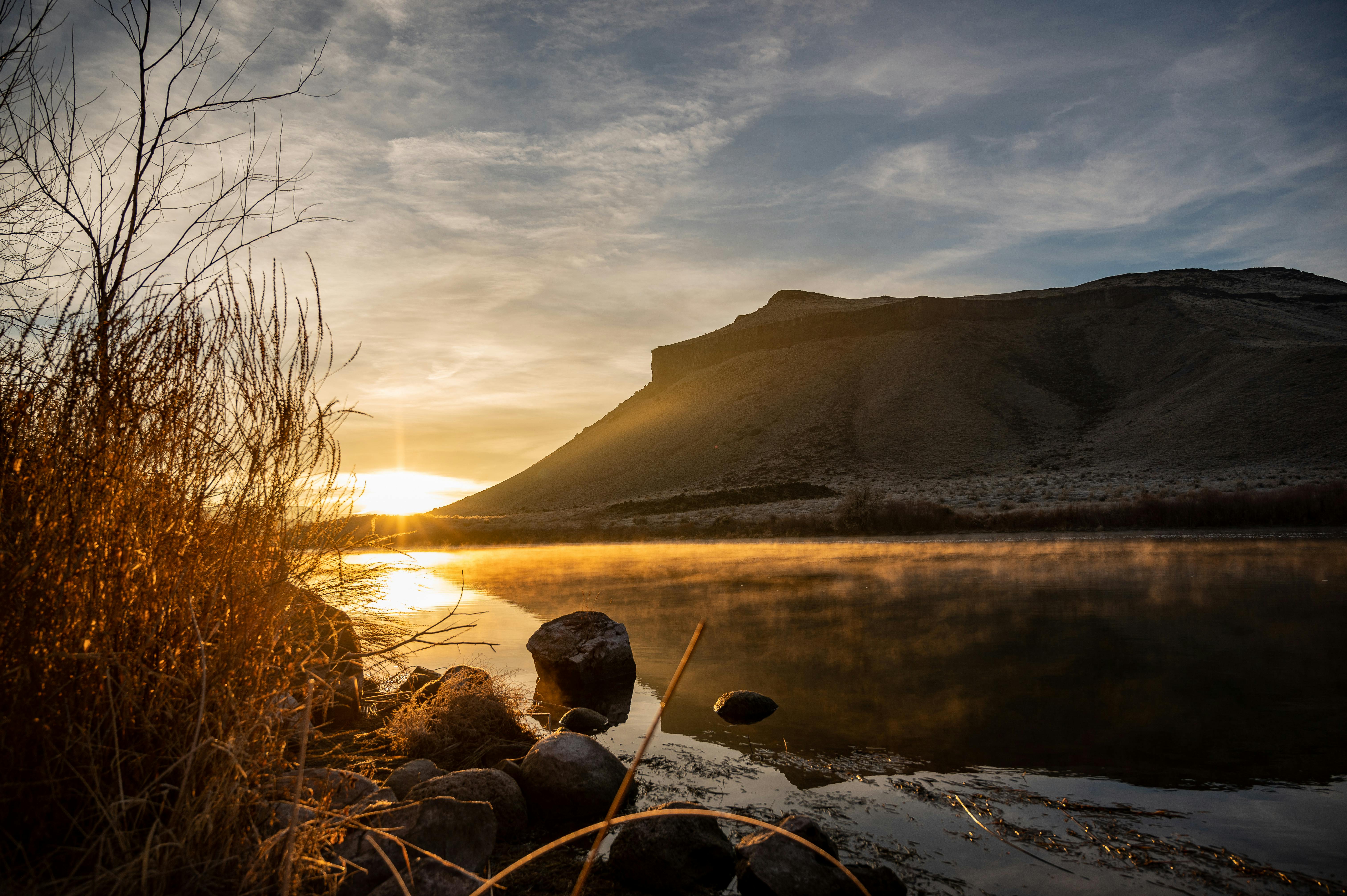 在僻静的山湖上，日出宁静，倒影朦胧，轮廓崎岖