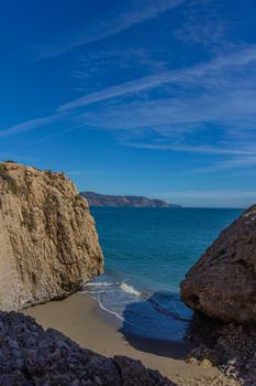 Breathtaking view of the cliffs and beach at Nerja, Spain, under a clear summer sky.