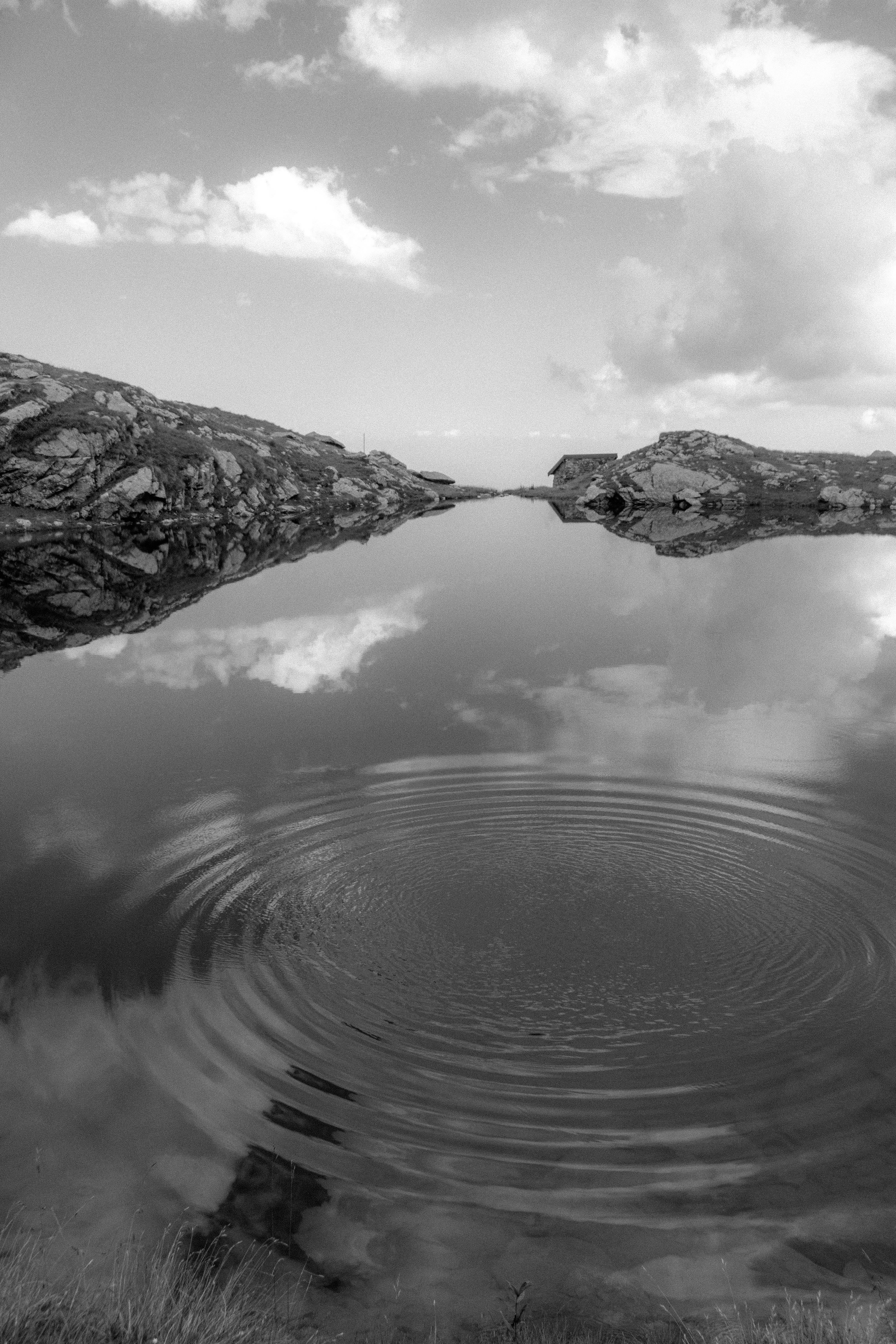 Tranquil landscape of a reflective lake with ripples and clouds.