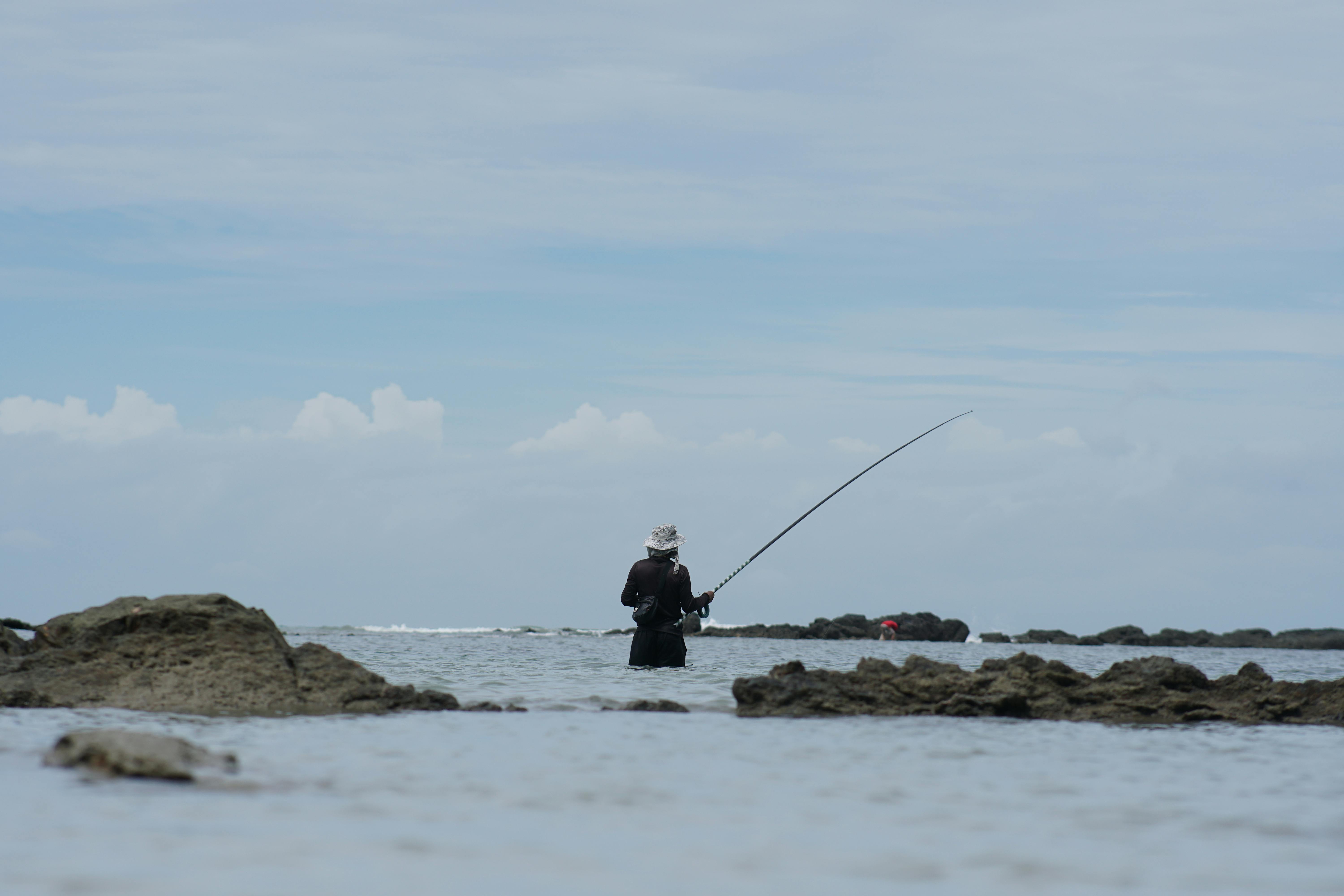 fisherman sits in a chair on the beach with fishing rods and