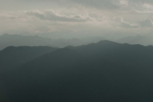 Serene view of misty mountain ranges at dusk in Mottarone, Italy.