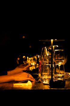 A romantic dining table with glasses and candles in a dimly lit ambiance, highlighting an intimate setting.