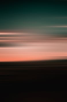 A serene abstract photo of a blurred sunset on the horizon with muted colors.