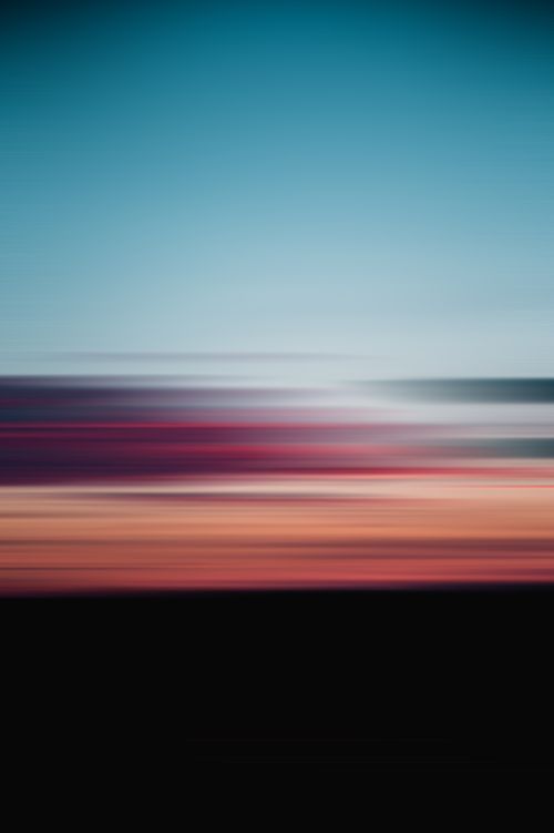 Free Blurred sunset capturing vibrant red, blue and orange hues merging in an abstract sky. Stock Photo