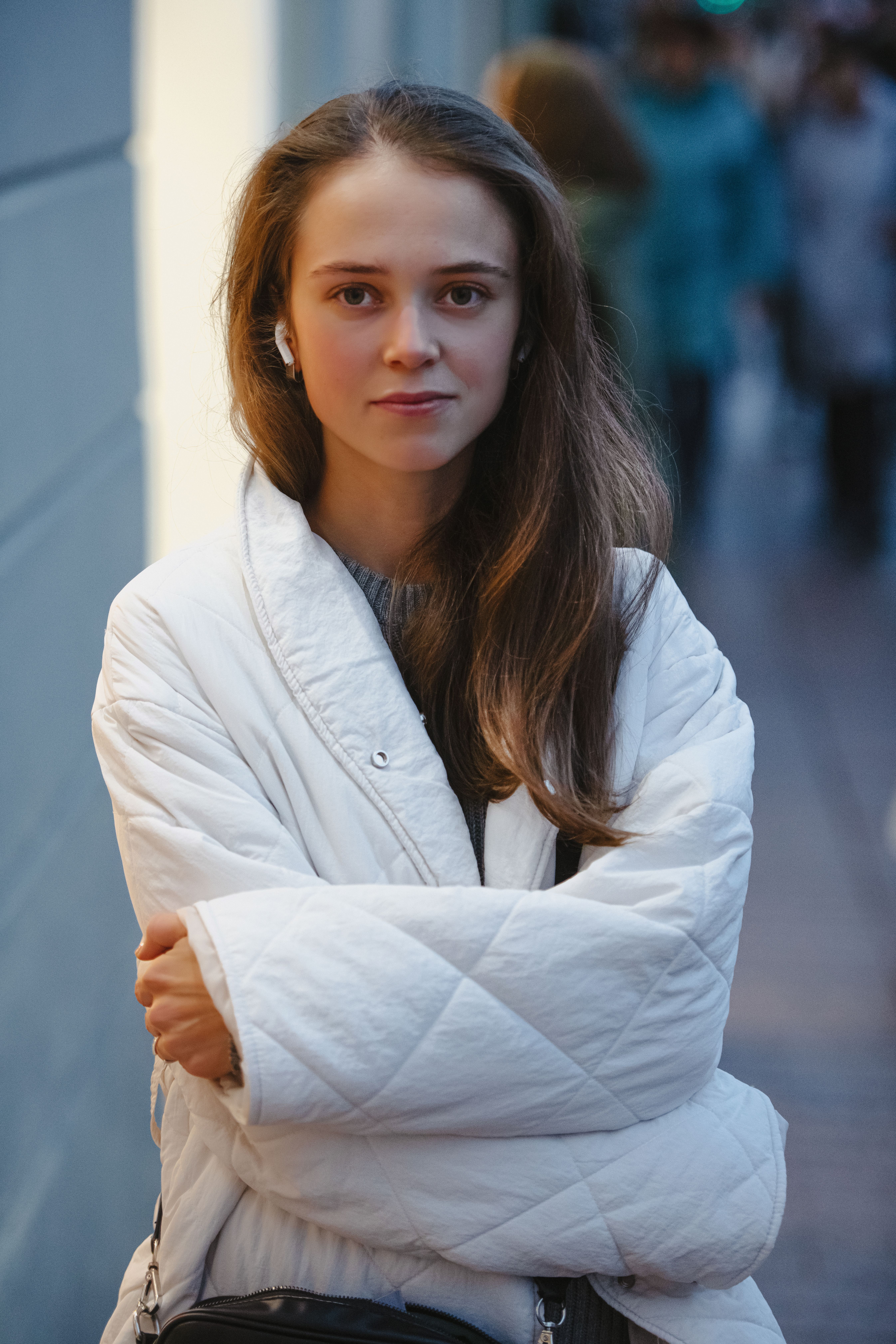 Portrait of a young woman in a white jacket in an urban setting, showcasing modern fashion.