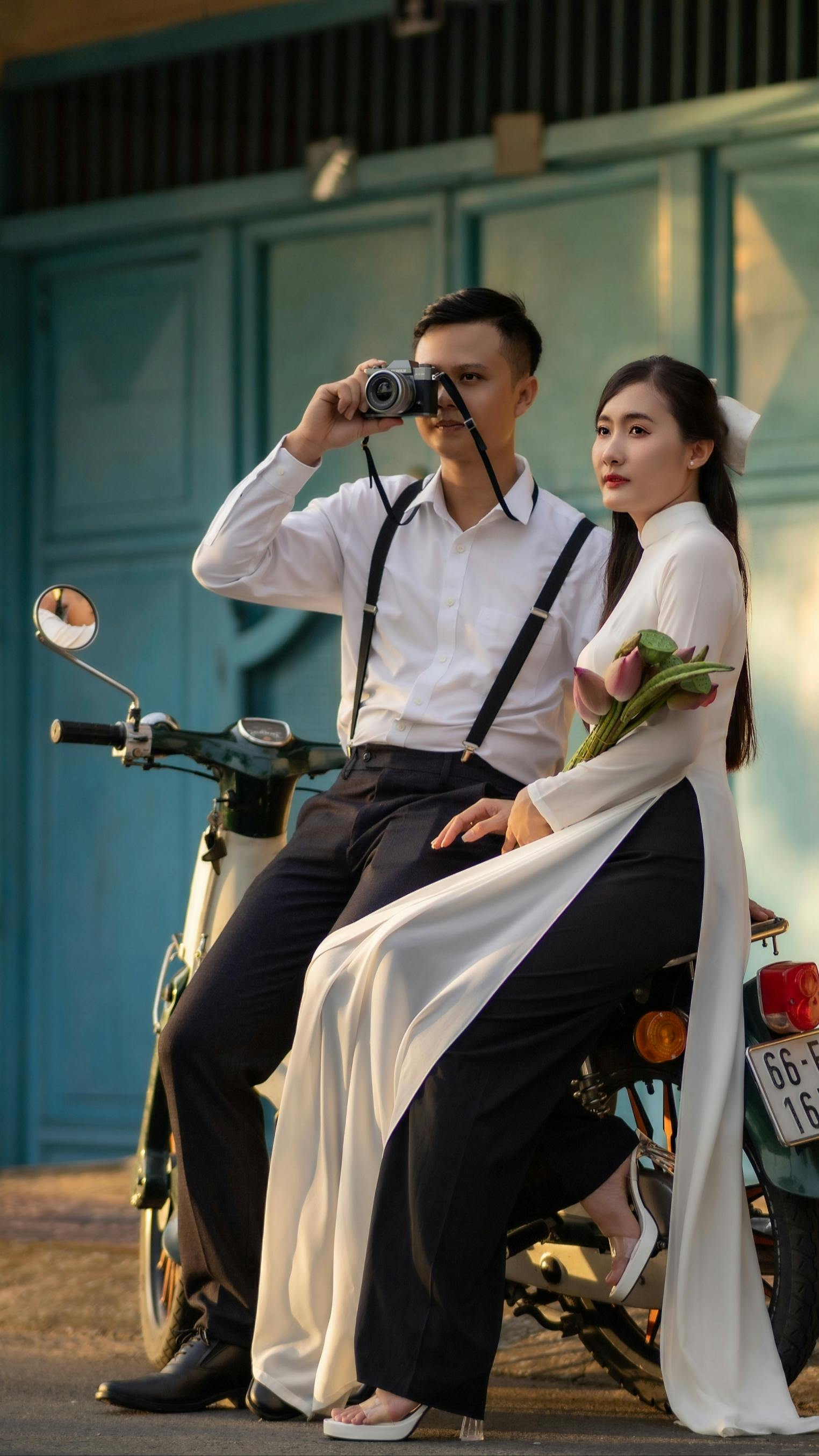 Elegantly dressed couple poses on a vintage motorcycle, capturing a charming moment.