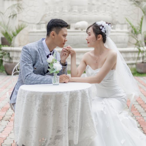 Newlyweds Sitting by Table and Holding Hands