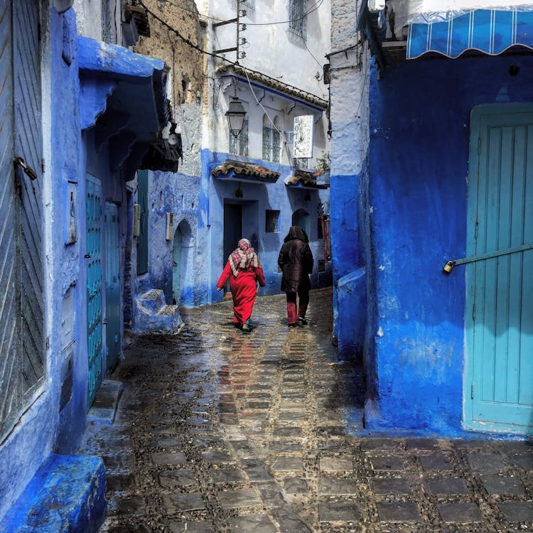 Two Person Walking Between Buildings