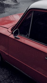 Close-up of a vintage red car in the rain, showcasing a classic Fiat design.
