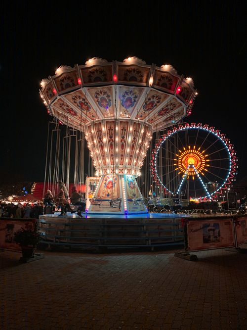 Free Beautifully lit carousel and Ferris wheel at night in Berlin's festive fairground. Stock Photo