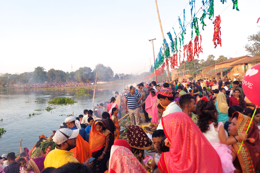 Crowd celebrating a traditional festival by the lake in Birpur, India with colorful attire and decorations.