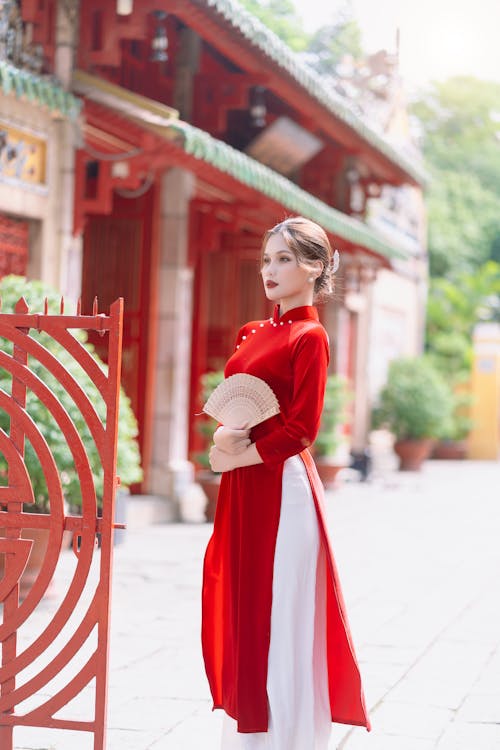 Woman in Elegant Traditional Red Dress Standing in a Yard