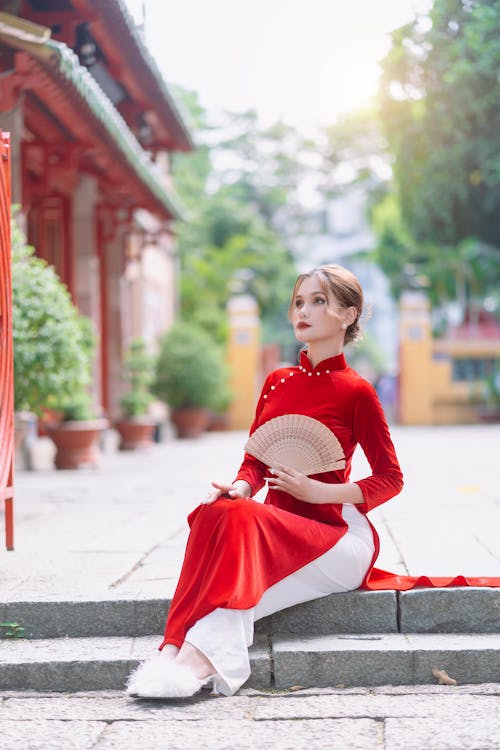 Woman in Long Red Dress Holding a Fan