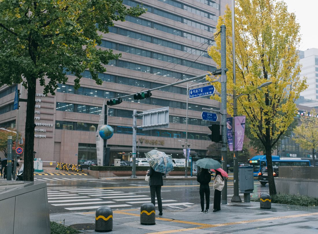 Pedestrians with umbrellas on a rainy Seoul street