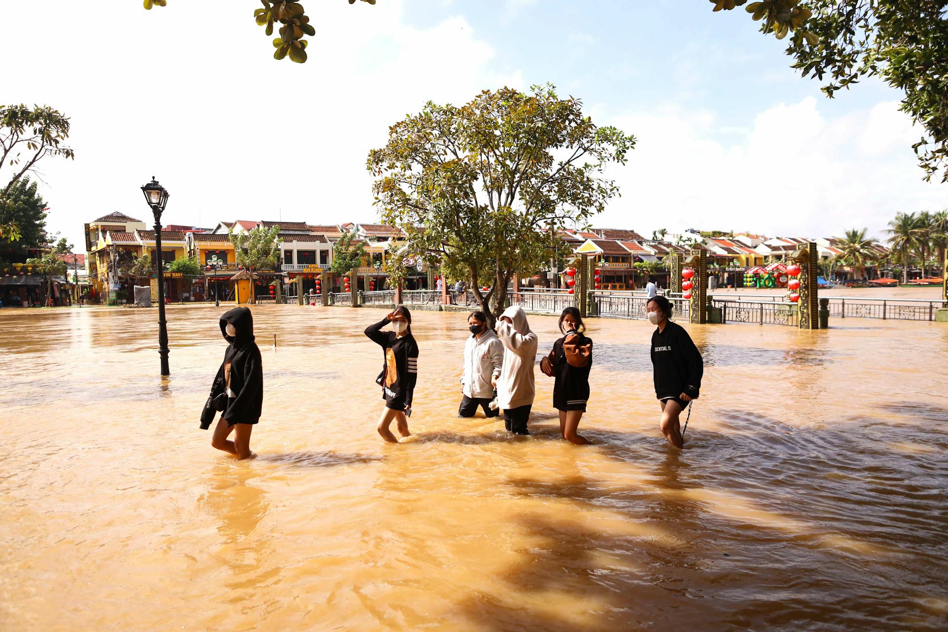 A group of people walking through floodwaters in an urban area, showcasing a natural disaster.