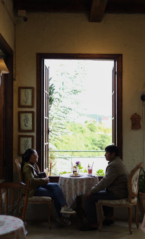 Man and Woman Sitting at the Table by the Window in a Cafe