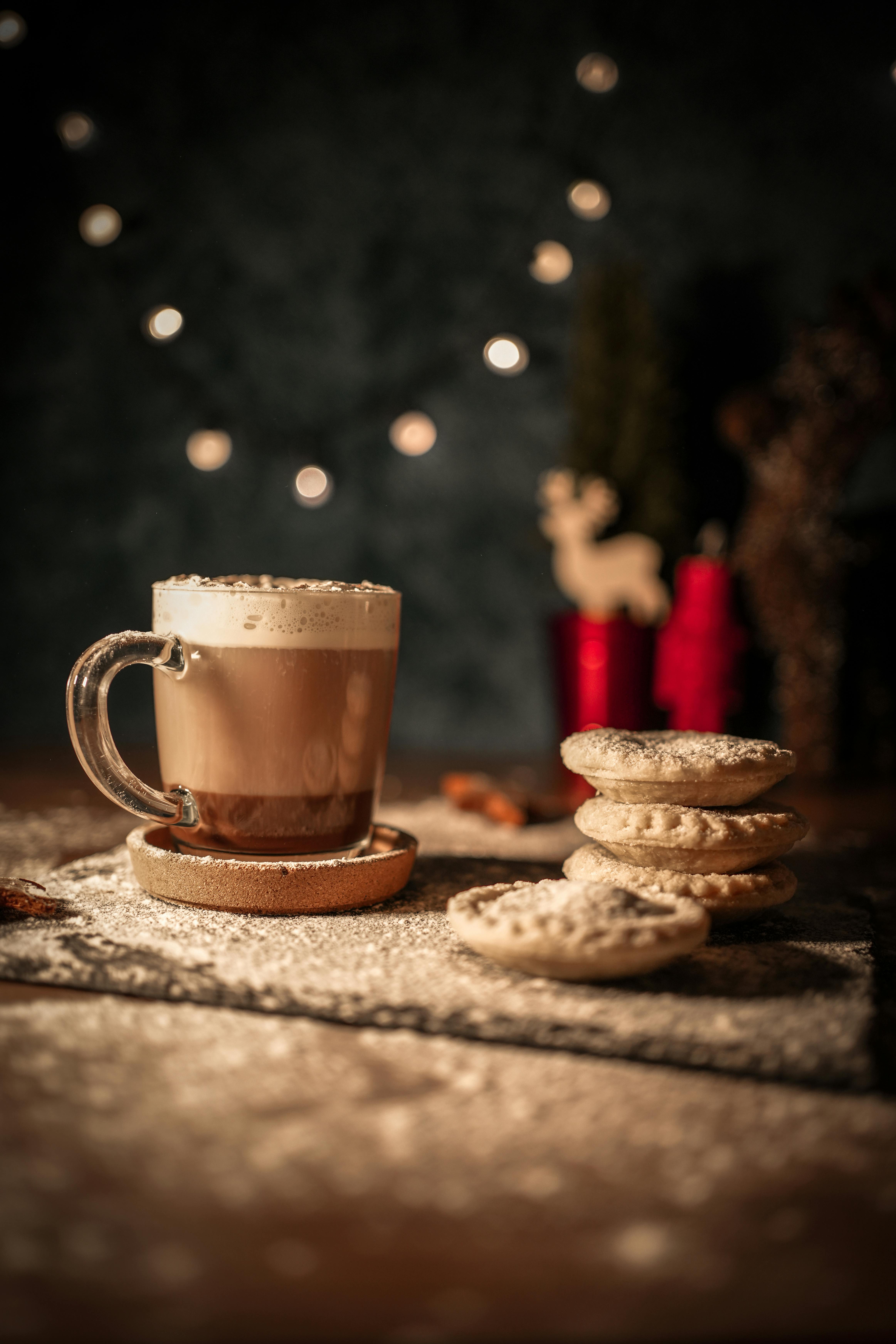 Warm winter setting featuring coffee and mince pies under Christmas lights.